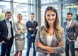 © Man888 - Portrait of young confidant business woman standing in the office smiling, co-workers and employees in the background