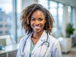 © Man888 - Confident African American female doctor beams with warmth and professionalism in a sterile clinic office, making eye contact with a gentle, reassuring smile.