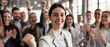 © Hound - A young woman cheers while celebrating a victory among a group of office workers clapping around her, inside a modern open space during the day