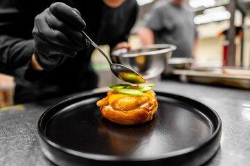 Wall Mural - A chef’s hand garnishing an elegant dish in a professional kitchen setting