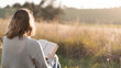 © Arcane Imaginarium - A woman reading or studying the Christian Bible outdoors in nature close to sunset