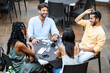© Lomb - Diverse friends enjoying outdoor dining: - Multicultural group laughing at restaurant terrace, young adults socializing, summer lifestyle, inclusive friendship