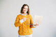 © Yauhen - A young woman enthusiastically points at a laptop, showcasing e-learning courses and educational software, perfect for promoting online education and job search websites. Isolated on white background.