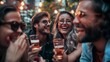 © Nicholas - A group of friends enjoy drinks and laughter outdoors under a canopy of string lights, creating a warm and joyful atmosphere, capturing the essence of fun and camaraderie.