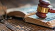 © Nicholas - Wooden judge's gavel resting on an ancient text book with intricate binding, set on a wooden surface, reflecting law, history, and scholarly study.
