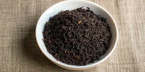 Poster - Dry black tea leaves in a white ceramic bowl, black tea, leaves, dry, ceramic, bowl, traditional, beverage, aromatic, organic