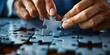 © inspiretta - A person is putting a puzzle piece into a puzzle. The puzzle is blue and has a lot of pieces