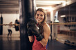 © Flamingo Images - Smiling woman standing by a punching bag in a boxing gym