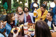 © Lomb - Exuberant friends enjoying outdoor feast with wine and beer, laughter-filled garden party under string lights