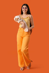 Canvas Print - Young happy woman in sunglasses with her adorable Bolognese dog on orange background