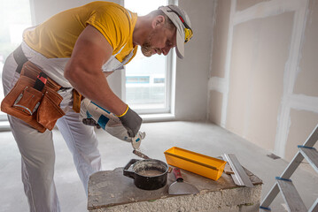 Wall Mural - The worker make a plasterboard ceiling. He doing preparation of the gypsum sealing mixture. A red plasterboard improve the fire resistance of ceiling structures.