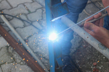 Welding man working on iron welding in construction site. Close up.