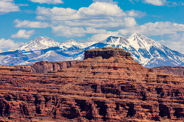 Wall Mural - Red sandstone cliffs with snow covered mountains in the background.