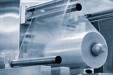 Poster - Automatic polyethylene plastic bag production machine with lighting effect. Close-up of the roller of the plastic bag production machine in the light blue scene. product packaging concept