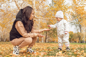 Heartwarming scene of mother and child playfully interacting in a fall setting. Family oriented content, parenting articles, or seasonal lifestyle advertisements.