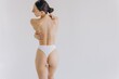 © anatoliycherkas - Cropped back rear view young nice lady woman with slim body perfect skin wearing nude top bra lingerie stand hold hands on thighs isolated on white background. Lifestyle diet fit concept