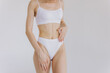 © anatoliycherkas - Close up shot of unrecognizable fit woman in lingerie isolated on white background. Torso of slim attractive female with flat belly in white underwear. Copy space for text.