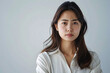 © ELmidoi-AI - An upset and disappointed Asian office girl in a professional setting against a white background.