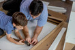 © volody10 - The son helps dad to collect furniture, nearby are tools and boards. Assembling furniture at home