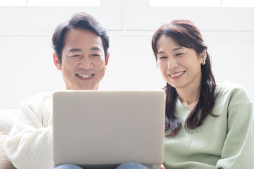 Wall Mural - Smiling middle-aged couple in their 50s looking at computer looking for search Front close-up