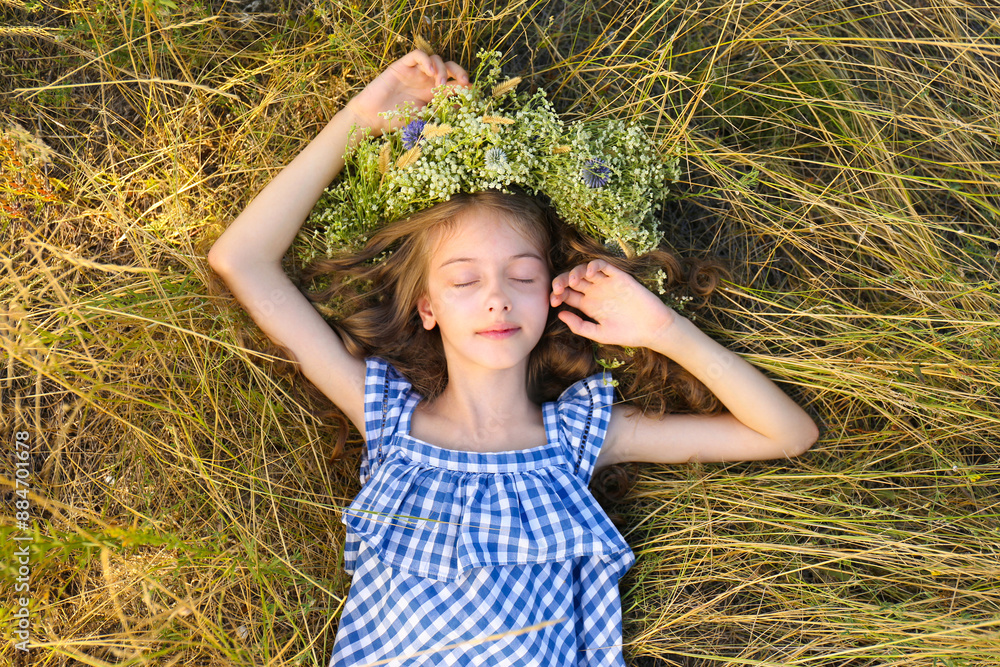 Cute little girl wearing wreath made of beautiful flowers on green ...