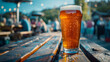 © Tijana - A pint of beer on a wooden table in an outdoor setting with people and lights in the background.