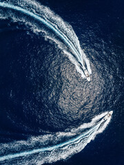 Wall Mural - aerial top down view of two motorboats cruising over the ocean with high speed and leaving a trail o