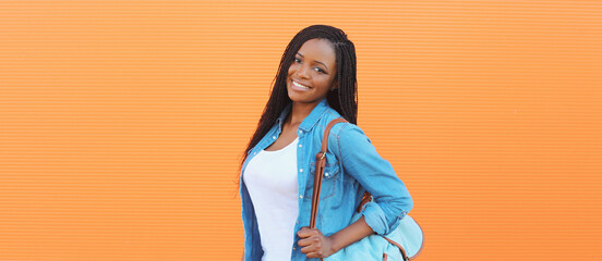 Wall Mural - Portrait of happy stylish young african woman in casual clothing, glasses posing in the city