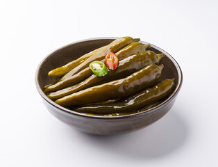 Close-up of pickled chili peppers with red and green pepper pieces on pottery bowl and white floor, South Korea
