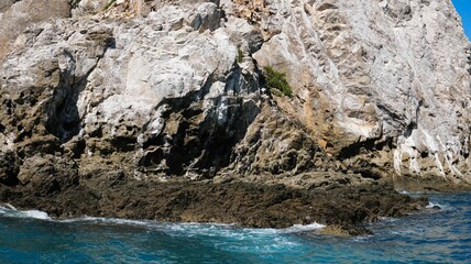 Sticker - Rocky coastal cliff with blue ocean water and clear sky in New Zealand