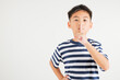 © sorapop - Young kid boy making finger on lips mouth silent quiet gesture, Happy Asian primary child marking silence for stop quiet, mute studio shot isolated on white background with copy space