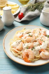 Canvas Print - Tasty pasta with shrimps, creamy sauce and cheese on light blue wooden table, closeup