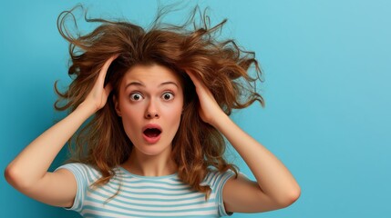 A woman with long hair is standing in front of a blue wall. She has her hands on her head and is looking surprised