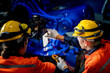 © ultramansk - engineers check control heavy machine robot arm. Diverse Team of Industrial Robotics Engineers Gathered Around Machine. Professional Machinery Operators repair electric robot on bright digital panel.