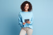 © Minimal Blue - Smiling Young Woman Holding a Digital Tablet and Posing Against a Light Blue Background