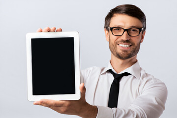 Poster - Smiling Business Man Showing Empty Tablet Computer Screen On White Studio Background. Mockup