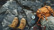 © DragonSlayer - A flat lay of outdoor adventure gear such as a backpack, hiking boots, and a compass on a rocky surface
