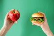 © Maryam - A vivid comparison of unhealthy and healthy food choices; a hamburger held in one hand and a fresh apple in the other against a green background