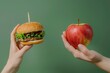 © Maryam - A vivid comparison of unhealthy and healthy food choices; a hamburger held in one hand and a fresh apple in the other against a green background