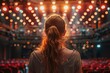© Azhorov - Curly-haired woman on stage, overlooking vacant seats under warm lights. Generative AI