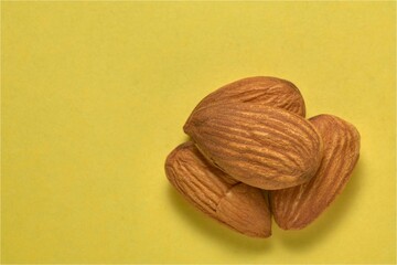 Close-up of a group of almonds on a yellow background.