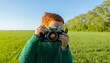 © Westend61 - Boy taking picture on old camera in field