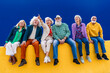 © Westend61 - Cheerful senior friends sitting on yellow wall
