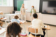 © InsideCreativeHouse - Lesson class during pandemic at school. Schoolchildren and teacher wearing protective medicine face masks against Covid19 coronavirus.