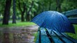 © CHAKKAPONG - A lively and detailed photo of a rain-soaked umbrella left on a park bench, hinting at a brief respite from the storm