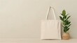 © ArtStockVault - Minimalist Beige Tote Bag Hanging Next to Potted Indoor Plant on Wooden Surface with Neutral Backdrop, Eco-Friendly Reusable Cloth Shopping Bag in Modern Home Decor Setting