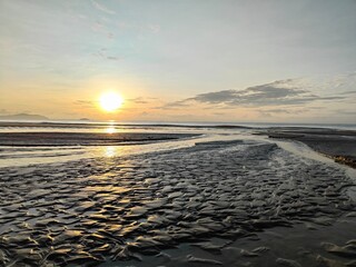 beautiful sunrise on a muddy beach. Dawn ambience on a beach with dramatic sunrise view