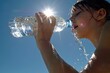 © Marina Demidiuk - Thirsty girl drinking water. Hot day. Young female drinking fresh water from plastic bottle against blue sky. Jogging, sport, cardio, healthy lifestyle. Refreshing. Low angle view. Summer heat.