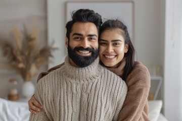 Portrait of a happy indian couple in their 30s wearing a thermal fleece pullover isolated on minimalist or empty room background