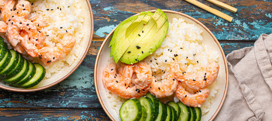 Poster - Two white ceramic bowls with rice, shrimps, avocado, vegetables and sesame seeds and chopsticks on colourful rustic wooden background top view. Healthy asian style poke bowl.